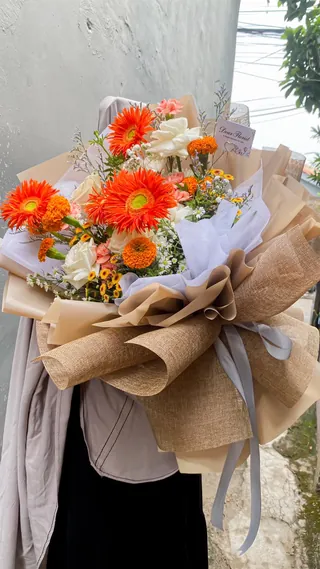 Sunset Gerbera: Gerbera oranye, mawar putih, matolia orange, aster putih, paso orange, baby breath, pikok putih, wrapping goni